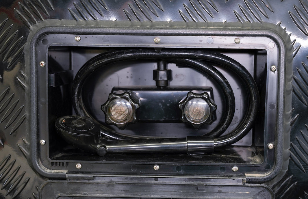 Hand adjusting the hot and cold valve on an RV outside shower