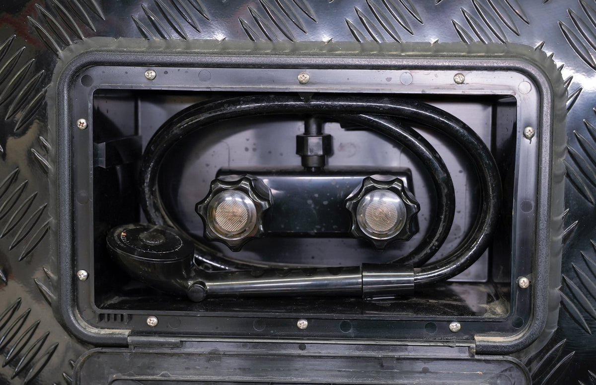 Hand adjusting the hot and cold valve on an RV outside shower
